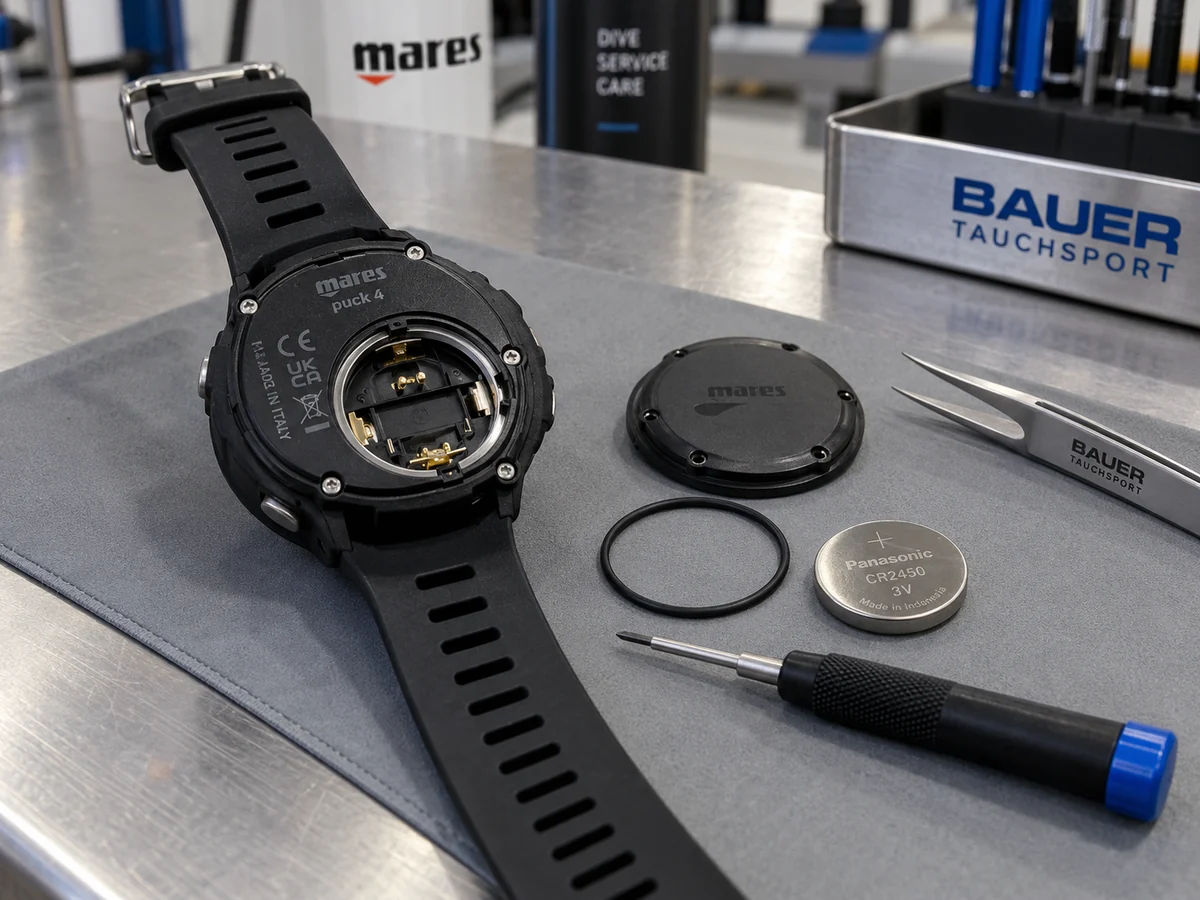 Geöffneter Tauchcomputer mit Batterie, O-Ring und Werkzeug